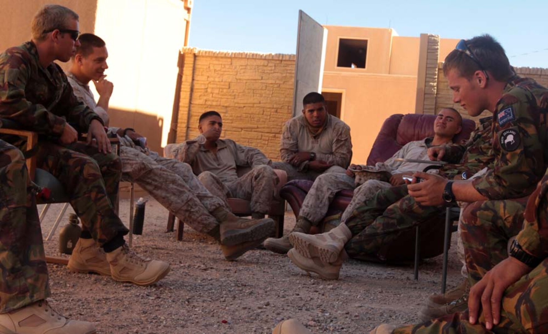 Marines and New Zealand Army soldiers, also known as Kiwis, sit in a circle on worn-out couches, chairs and benches as they wait for their next scenario in their counter insurgency exercise at Range 220A, June 20. The Marines and Kiwis made strong bonds during their down time as they found out just how much they had in common.