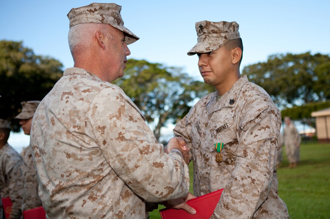 Sgt. Lionel J. Flores III shakes hands with Col. Brent S. Willson, commanding officer, Headquarters and Service Battalion, U.S. Marine Corps Forces, Pacific, after being awarded a Navy and Marine Corps Achievement Medal here July 2. Flores received the award for leading his section through an inspector-general’s inspection with no discrepancies. 