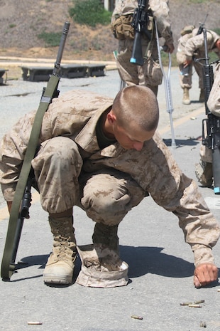 A recruit of Company M, 3rd Recruit Training Battalion, picks up brass from the 300-yard firing line during firing week aboard Edson Range, Weapons and Field Training Battalion, Marine Corps Base Camp Pendleton, Calif., Aug. 28.