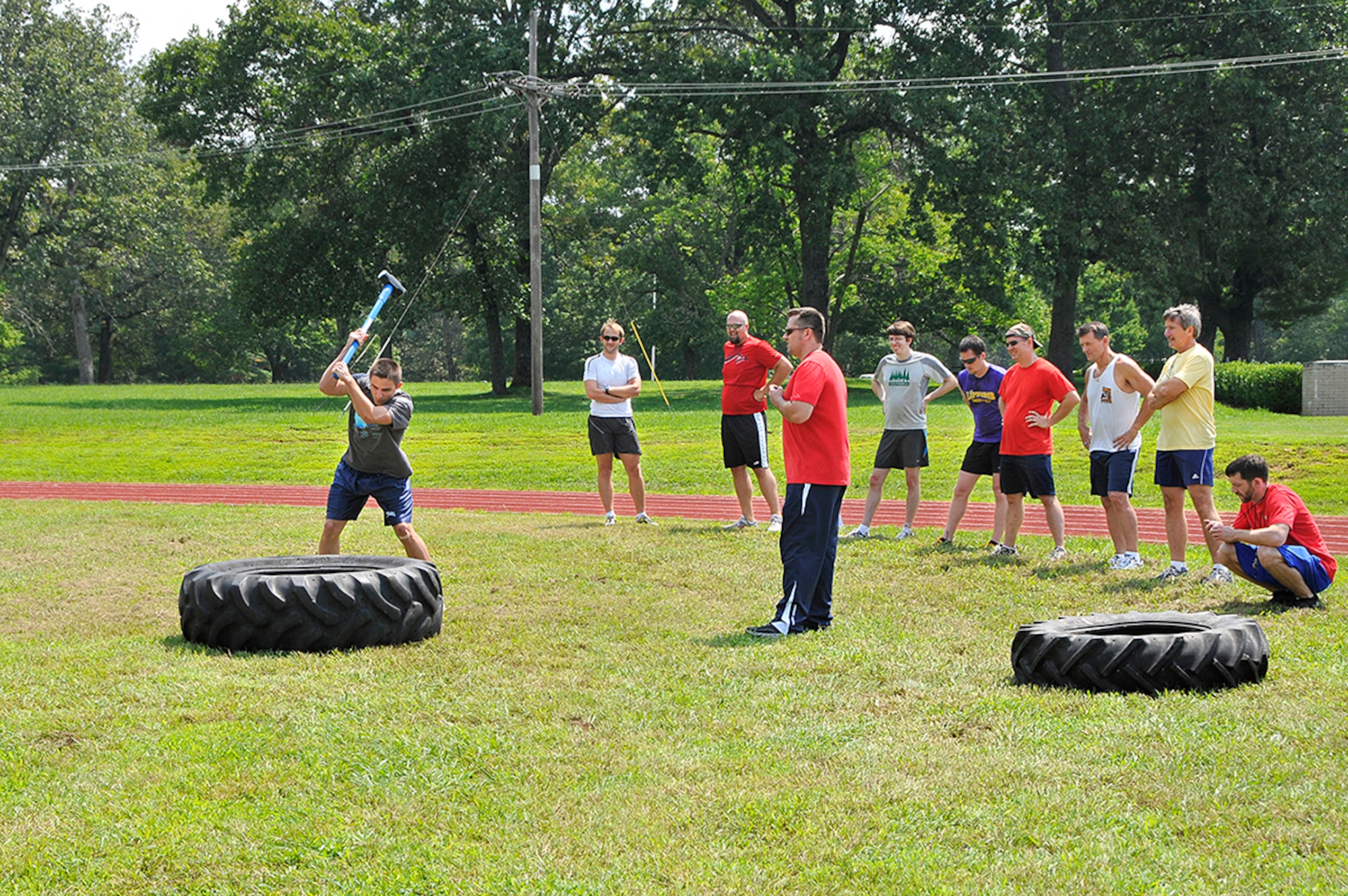 Aerospace Testing Alliance engineer Jordan Panter takes his turn hammering away at a tire while other Battlefield Day participants look on. Panter won the event, along with the 60-meter sprint. (Photo by Jacqueline Cowan)