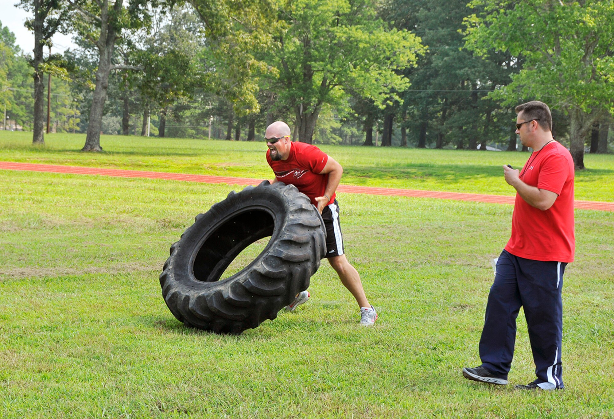 Aerospace Testing Alliance engineer Chad Overcast flips a 170-pound tire as AEDC Fitness Center programs coordinator Joe Watters keeps time. The tire toss was one of several events during Battlefield Day, a fitness competition held annually at the complex. (Photo by Jacqueline Cowan)