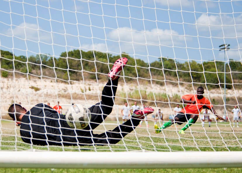 Dyess goalkeeper John Tomsich narrowly misses the ball shot by Luke forward Yawovi Kpogo Sept. 2, 2012, during the Defender’s Cup at San Antonio. During the first day of the tournament, teams were placed into groups of four and played each other to see where they would be placed in the tournament’s bracket. Team Dyess went undefeated during the group portion, beating Team Hill, Columbus and Medina. This placed them No. 1 in their group and fifth overall in the 22-team competition. Having the top seed in their group gave Dyess a first-round bye on the second day of the tournament, where they faced Luke AFB. In a tough game, Luke defeated Dyess in penalty kicks after tying 1-1 during regulation. (U.S. Air Force photo by Airman 1st Class Damon Kasberg/Released)