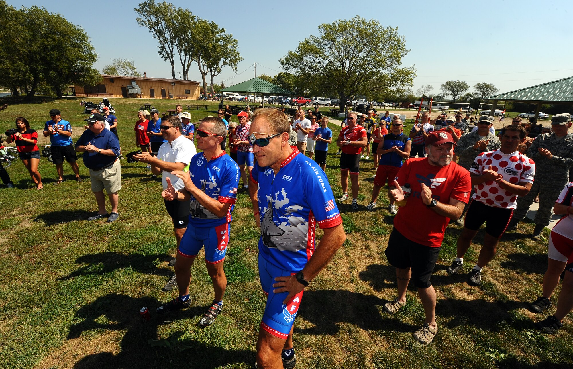 A crowd of cyclists representing local area riders, the Bellevue Bike Club and the original five riders participating in the Long Road Home project listen to keynote speakers from both wing leadership and the Offutt Advisory Council at a picnic held at the Base Lake on Offutt Air Force Base, Neb., Aug. 30.  The Long Road home project is comprised of five veteran riders who are peddling across the country to raise money and awareness concerning America’s veteran community.  (U.S. Air Force photo by Josh Plueger/Released).
