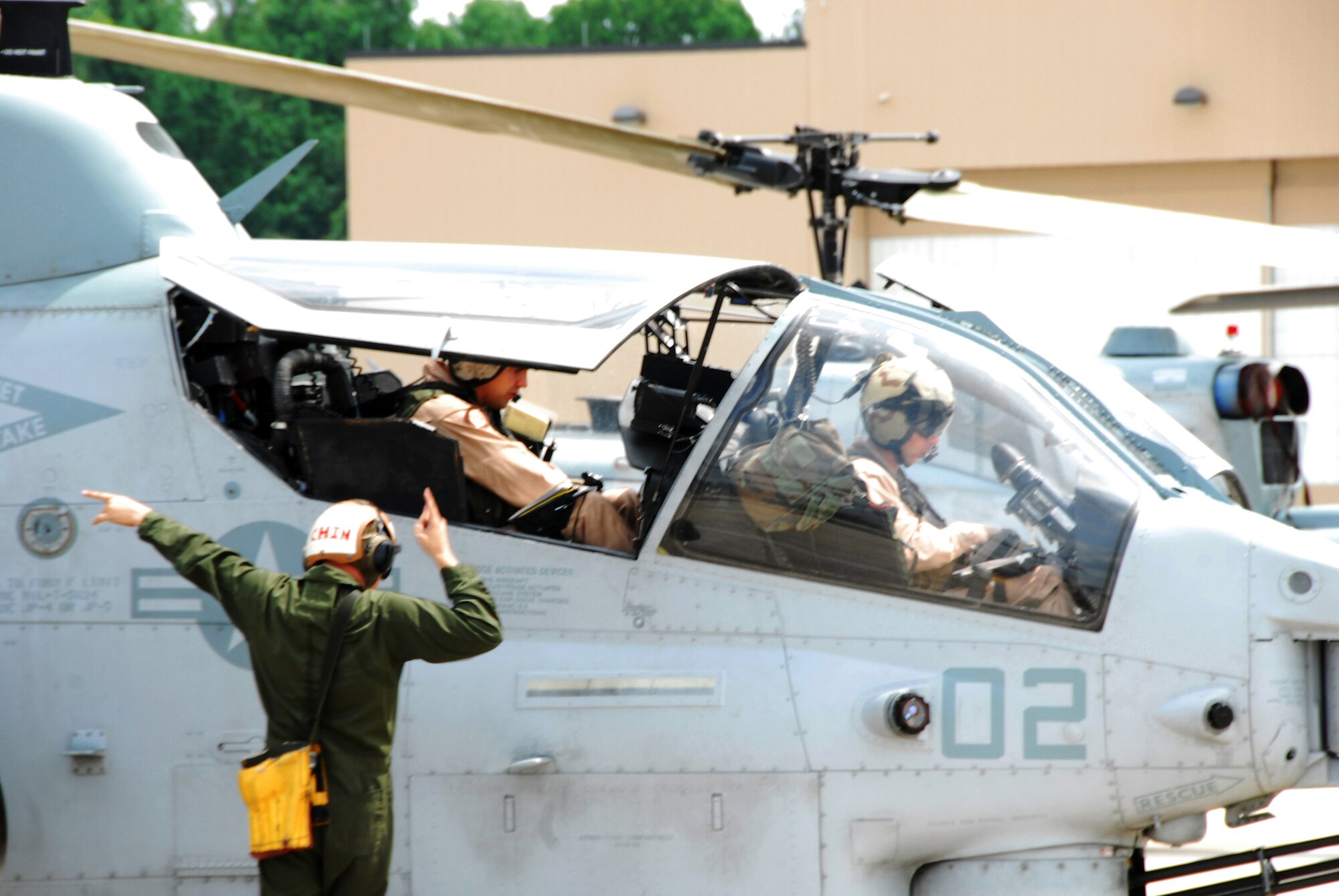 Corporal Marcus Lewis signals the “Power on Engine 2” command to Lt. Col. David Steele,  MAG-49 commanding officer, and Capt. Douglas Hackl, HMLA-773 operations officer, as they prepare their AH-1 Super Cobra for a flying mission in Georgia training areas. (U.S. Air Force photo/Ed Aspera Jr.)
