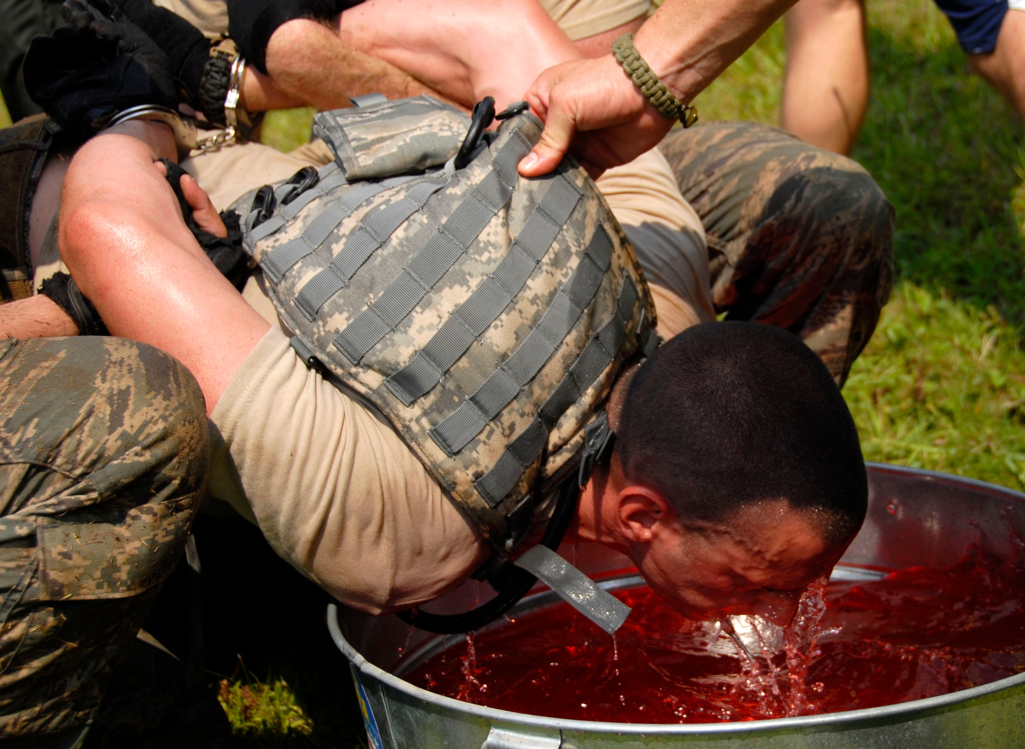 Staff Sgt. Christopher Sixt of the 103rd Security Forces Squadron is handcuffed as he attempts to retrieve a handcuff key with his mouth from a bucket of capsaicin, the ingredient used in police pepper spray. Sixt is participating in the PT portion of the Connecticut SWAT Challenge in West Harford, Conn., Aug. 23, 2012. (U.S. Air Force photo by Senior Airman Jennifer Pierce/Released)