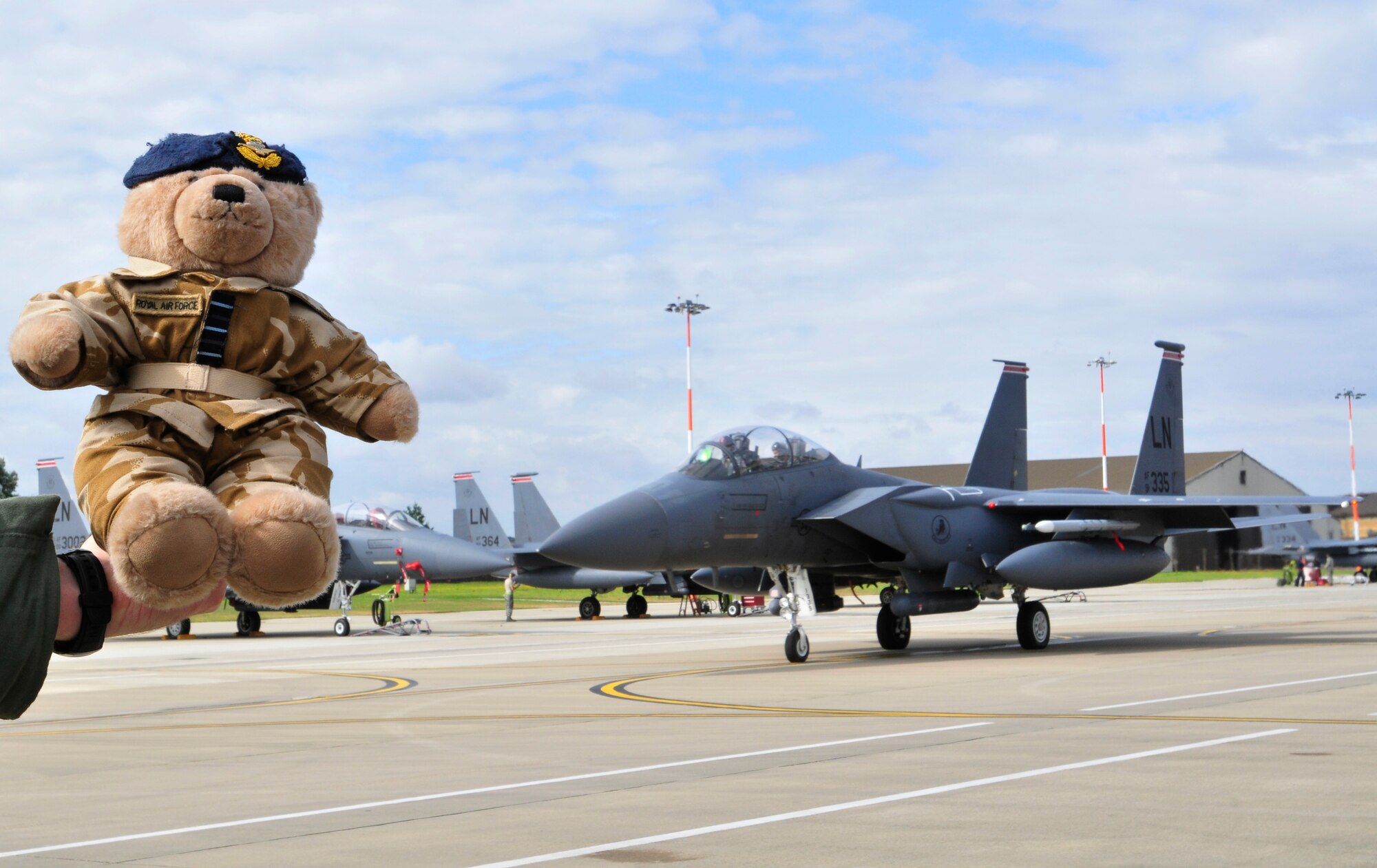 ROYAL AIR FORCE LAKENHEATH, England - Wing Commander Bear is held as an F-15 taxis for take-off on the flightline Aug. 3, 2012. Bear has been visiting bases since his visit to Nellis Air Force Base, Nevada two years ago, where he flew with RAF 3 Squadron Harriers for two weeks. Bear will be auctioned off along with photos of all his visits for the Royal Air Force Valley charity in North Wales, the RAF Benevolent Fund and Medrwn Mon Anglesey charities. (U.S. Air Force photo by Senior Airman Tiffany M. Grigg) 