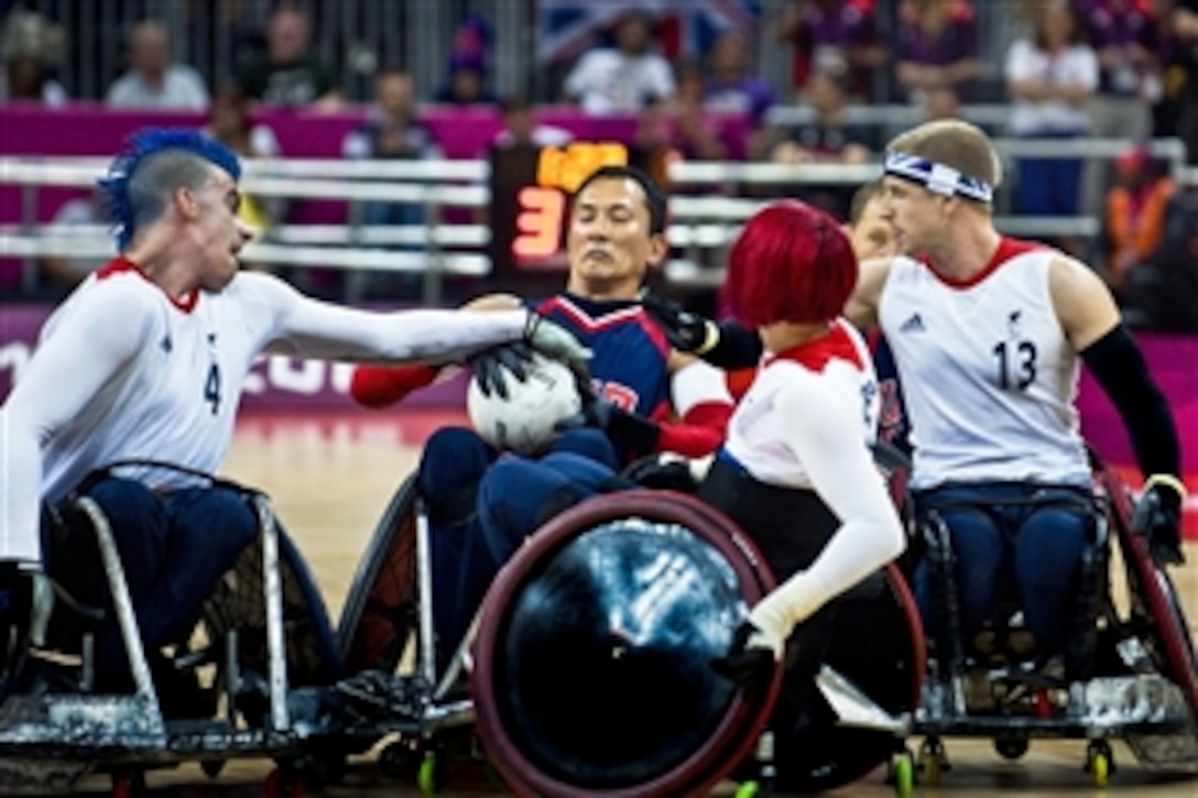 William Groulx, U.S. wheelchair rugby captain and retired Navy sailor, holds the ball as members of the British team try to take it during the 2012 Paralympic Games in London, Sept. 5, 2012.