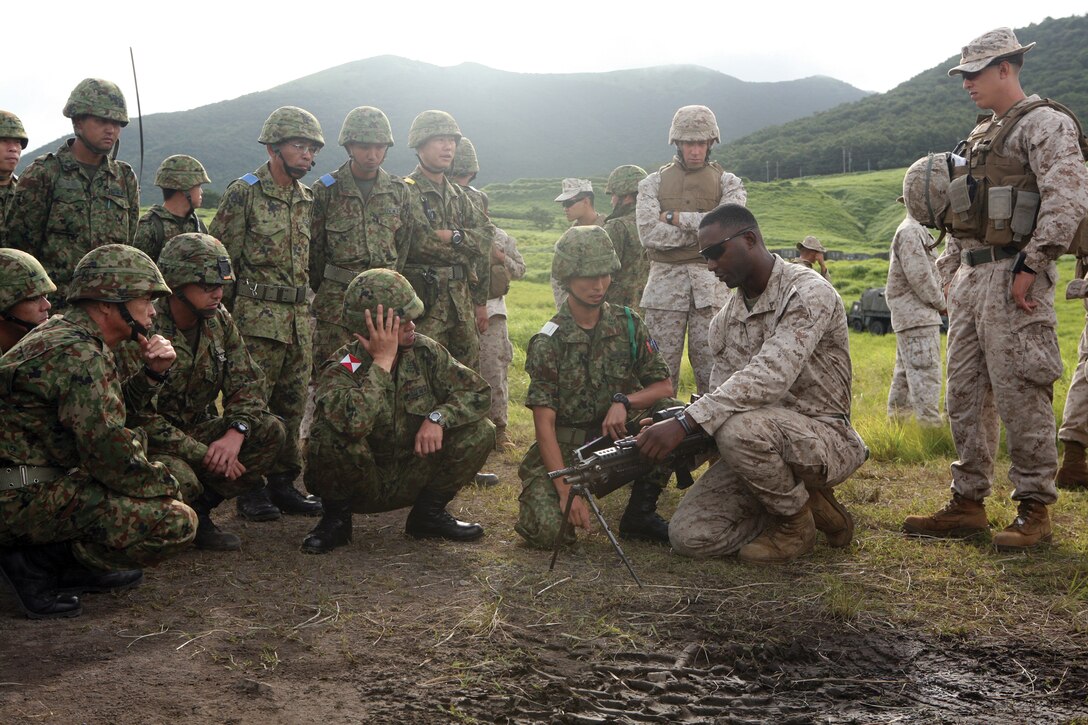 Lance Cpl. Warren J. Jackson explains how the M240B medium machine gun functions during Exercise Forest Light 12-01 at the Hijudai Maneuver Area, Oita prefecture, Japan, Aug. 24. The bilateral exercise provided the service members the opportunity to work under stressful conditions during live-fire training. Jackson is a rifleman with Company G, 2nd Battalion, 3rd Marine Regiment, 3rd Marine Division, III Marine Expeditionary Force. The JGSDF members are with the 41st Infantry Regiment.
