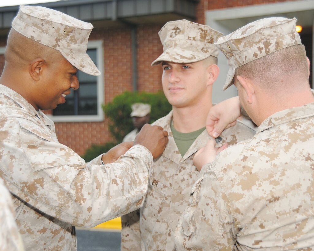 Gunnery Sgt. Morgon Latimore, left, and Sgt. Brandon Wilson, right, pin chevrons on Sgt. Edward Peifer during his meritorious promotion Aug. 21 in front of Building 3500, here.