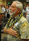 An audience member renders respects as the National Anthem and Hawai'i Pono'I are played during the opening ceremonies for the 11th Anniversary of the Joint Venture Education Forum Annual Meeting, held at the Ford Island Conference Center, Ford Island, Hawaii Aug. 30, 2012. The JVEF mission is to provide continuous coordination through partnerships and open dialogue, in order to promote an understanding of and implement initiatives to address the needs of military children and families and to facilitate support for Hawaii's public school students. (U.S. Air Force photo/Tech. Sgt. Jerome S. Tayborn)