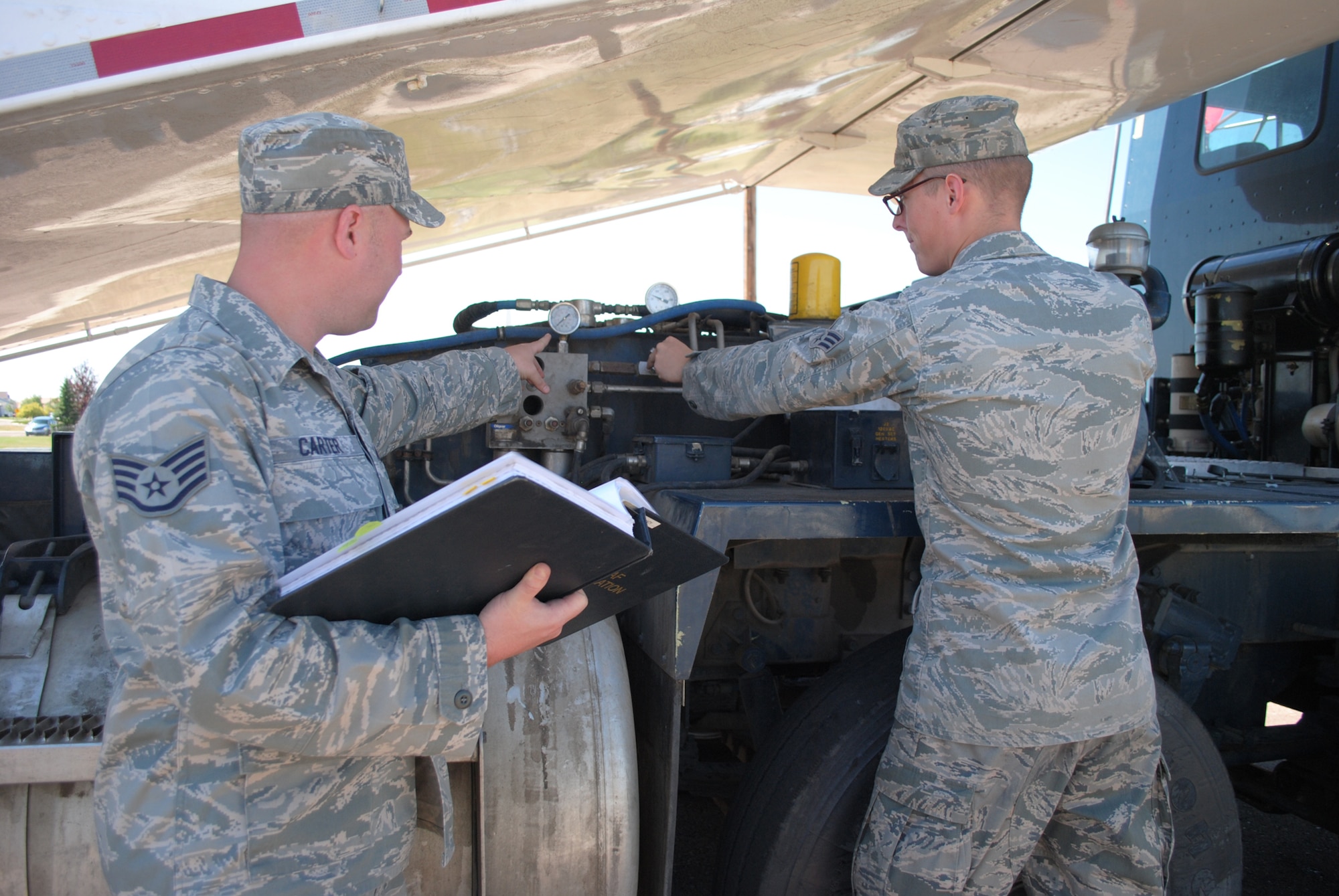 Staff Sgt. James Carter, 341st Missile Maintenance missile handling quality assurance evaluator, and a trainer for the MHT Global Strike Challenge team, corrects Senior Airman Andy Wellman, 341st MMXS MHT technician, as he troubleshoots on a payload transporter at the T-9 training facility on Aug. 16. (U.S. Air Force photo/Airman 1st Class Katrina Heikkinen)