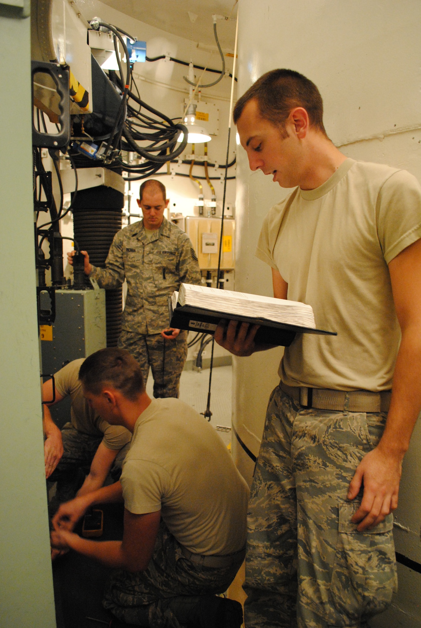 Senior Airman Dustin Melton, 341st Missile Maintenance Squadron electro-mechanical team chief, reads technical orders to his teammates during a practice scenario on Aug. 16. Tech. Sgt. Matthew Ricker, 341st MMXS EMT critical task supervisor, background, is the trainer for the EMT team representing Malmstrom in the upcoming Global Strike Challenge. (U.S. Air Force photo/Airman 1st Class Katrina Heikkinen)