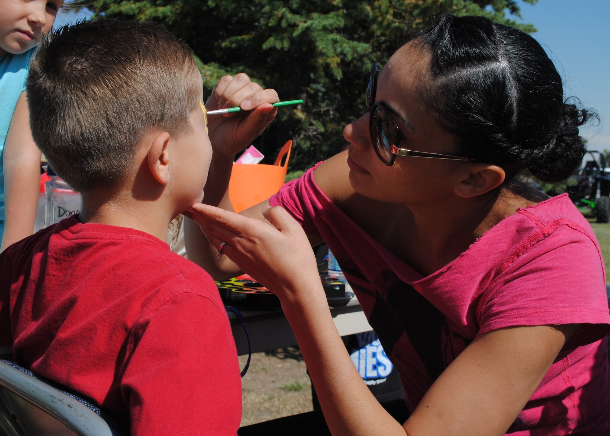 Trevan Burns, 8, waits patiently as Senior Airman Sulai Baddour, 341st Force Support Squadron evaluations technician, paints his face at the annual military appreciation picnic at Sun Plaza Park on Aug. 24. The picnic gathers more than 2,000 Team Malmstrom members each year. (U.S. Air Force photo/Airman 1st Class Katrina Heikkinen)