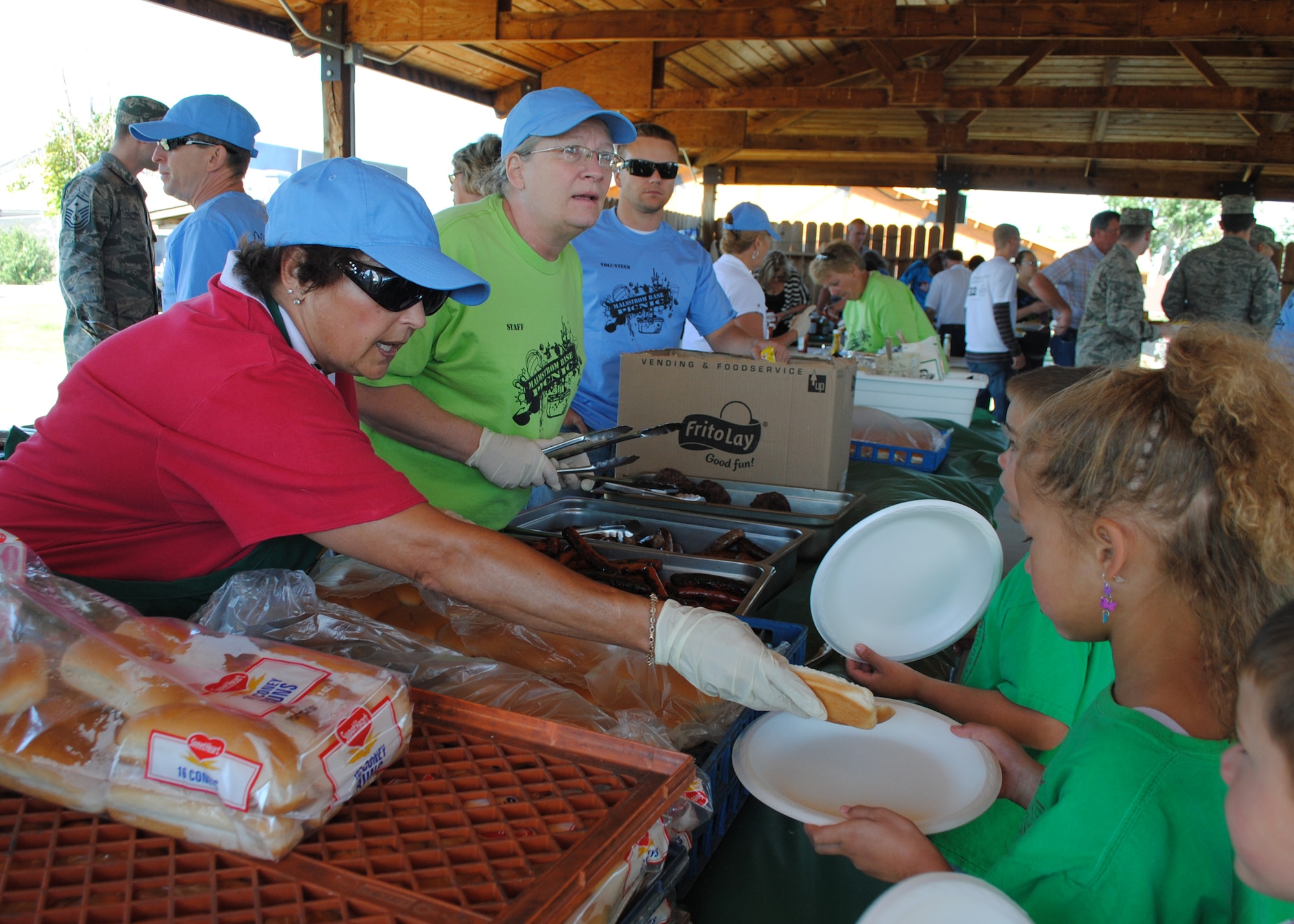 Dimmer Kjelsrud, Military Affairs Committee member, left, hands a hot dog to children at the annual base picnic. More than 100 volunteers helped at the picnic this year, serving a free lunch to more than 2,500 people. (U.S. Air Force photo/Airman 1st Class Katrina Heikkinen)