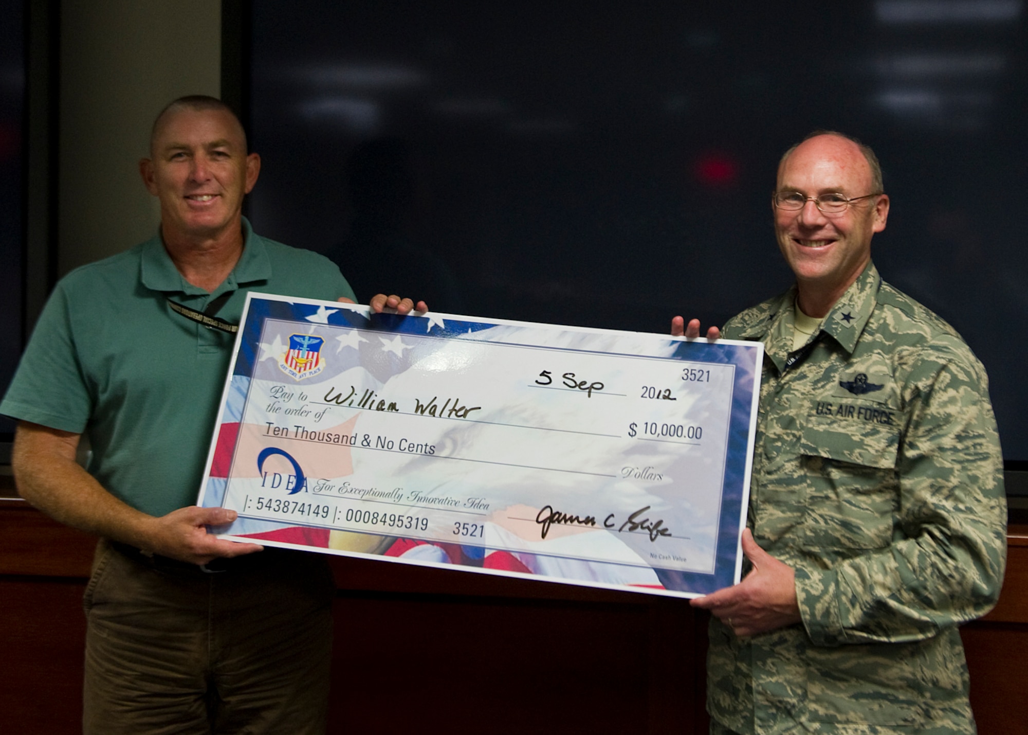 U.S. Air Force Brig. Gen. Michael Kingsley, Air Force Special Operations Command vice commander, poses with William Walter, AFSOC program analyst, during a ceremony held at the AFSOC headquarters building on Hurlburt Field, Fla., Sept. 5, 2012. Walter submitted a proposal to the IDEA program and was rewarded with a $10,000 check. (U.S. Air Force photo/Airman 1st Class Christopher Williams)