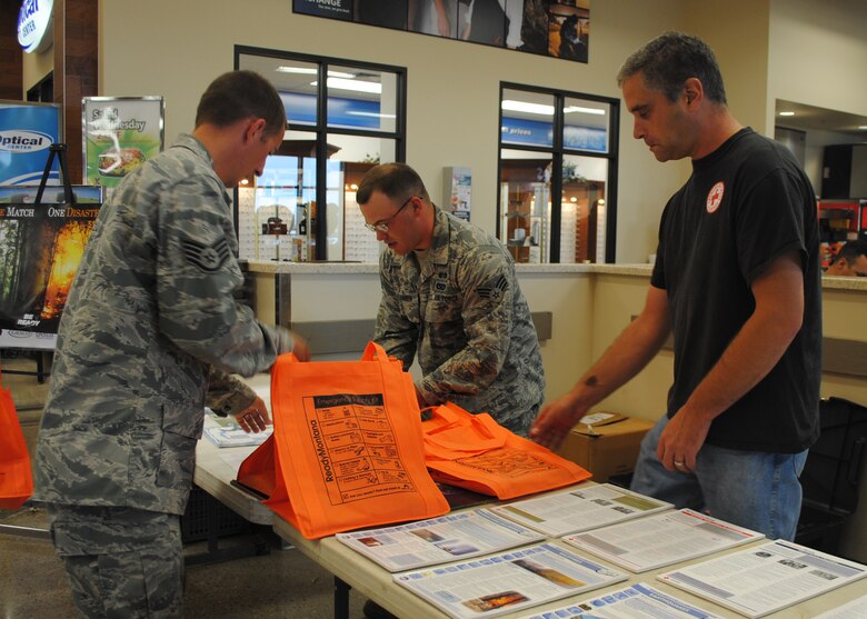 (From left to right) Staff Sgt. Nathan Sisk, 341st Civil Engineer Squadron emergency management technician, Senior Airman Thomas Hermansen, 341st CES emergency management technician, and Kevin Merszewski, Great Falls’ Red Cross preparedness coordinator, arrange bags to hand out to customers at the Exchange on Sept. 4. Malmstrom’s emergency management office and Great Falls Red Cross teamed up to host an information fair at the Exchange to coincide with the celebration of National Preparedness Month. Customers had a chance to win an emergency first aid starter kit. (U.S. Air Force photo/Airman 1st Class Katrina Heikkinen) 