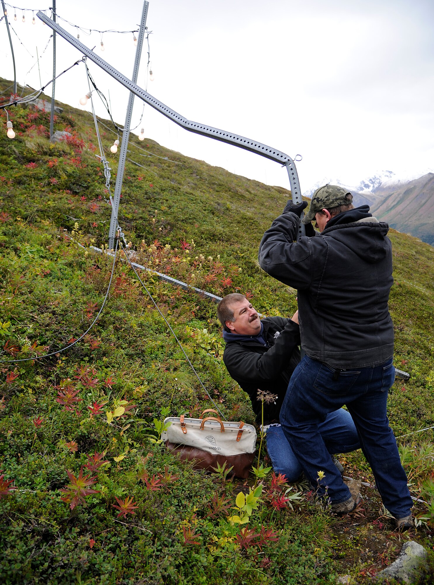 Donnie Bull, Shaw Environmental and Infrastructure Group lead electrician, and Tom Ojala, Shaw electrician journeyman, repair damage to the summit star on Mount Gordon Lyon, Sept. 6, 2012. The star will be lit Sept. 11 in memory of those who lost their lives in the 9/11 terrorist attacks and will then be relit the day after Thanksgiving. The star will stay lit from that time until the last of the mushers from the Iditarod Trail Sled Dog Race crosses the finish line. (U.S. Air Force photo/Staff Sgt. Zachary Wolf)