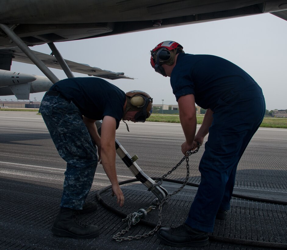 Navy crew chiefs remove the arresting cable from the EA-6B Prowler's arresting hook during an annual certification of the barrier arrestor kit Aug. 17, 2012 at Joint Base Andrews, Md. 11th CES Airman annually certify the BAK to ensure proper function in case of an actual emergency. (U.S. Air Force photo/Senior Airman Perry Aston)