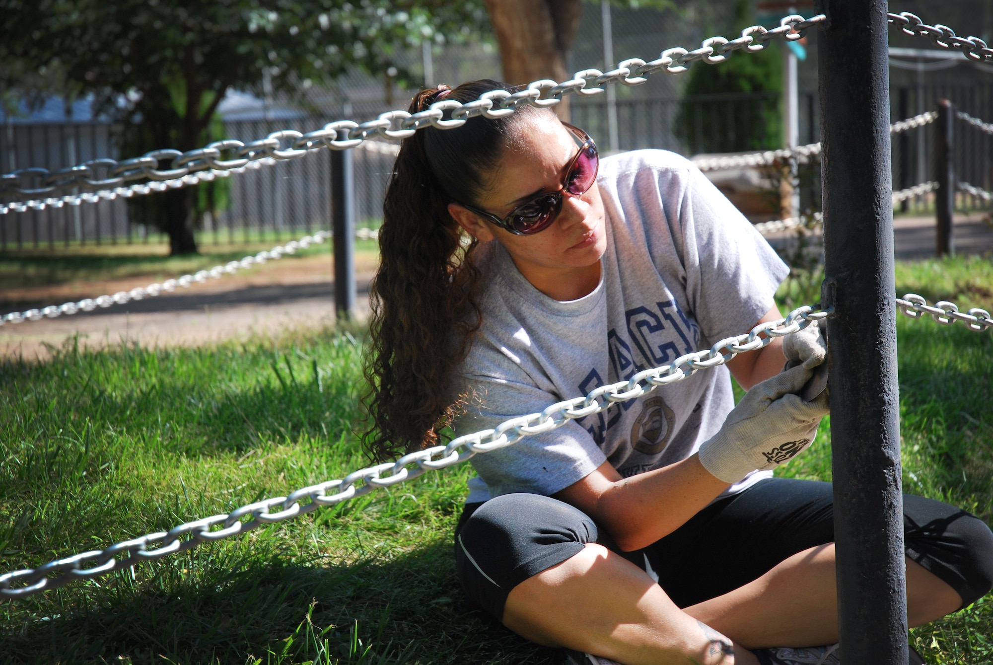 A volunteer from Cannon Air Force Base, N.M., scrapes off old paint and rust from a pole at The Hillcrest Zoo, Clovis, N.M., Aug. 31, 2012. Cannon's 5/6ers organized and coordinated the volunteer beautification project between base personnel and the zoo.  (Courtesy photo)  