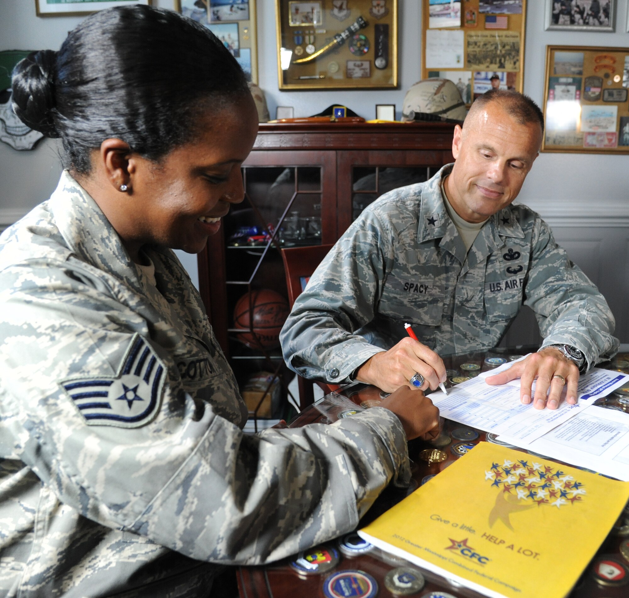 Staff Sgt. Brandy Cotton, 335th Training Squadron and 81st Training Wing combined federal campaign marketing representative, points out the signature line of a CFC pledge form to Brig. Gen. Bradley Spacy, 81st TRW commander, Sept. 6, 2012, in his office at Keesler Air Force Base, Miss.  (U.S. Air Force photo by Kemberly Groue)