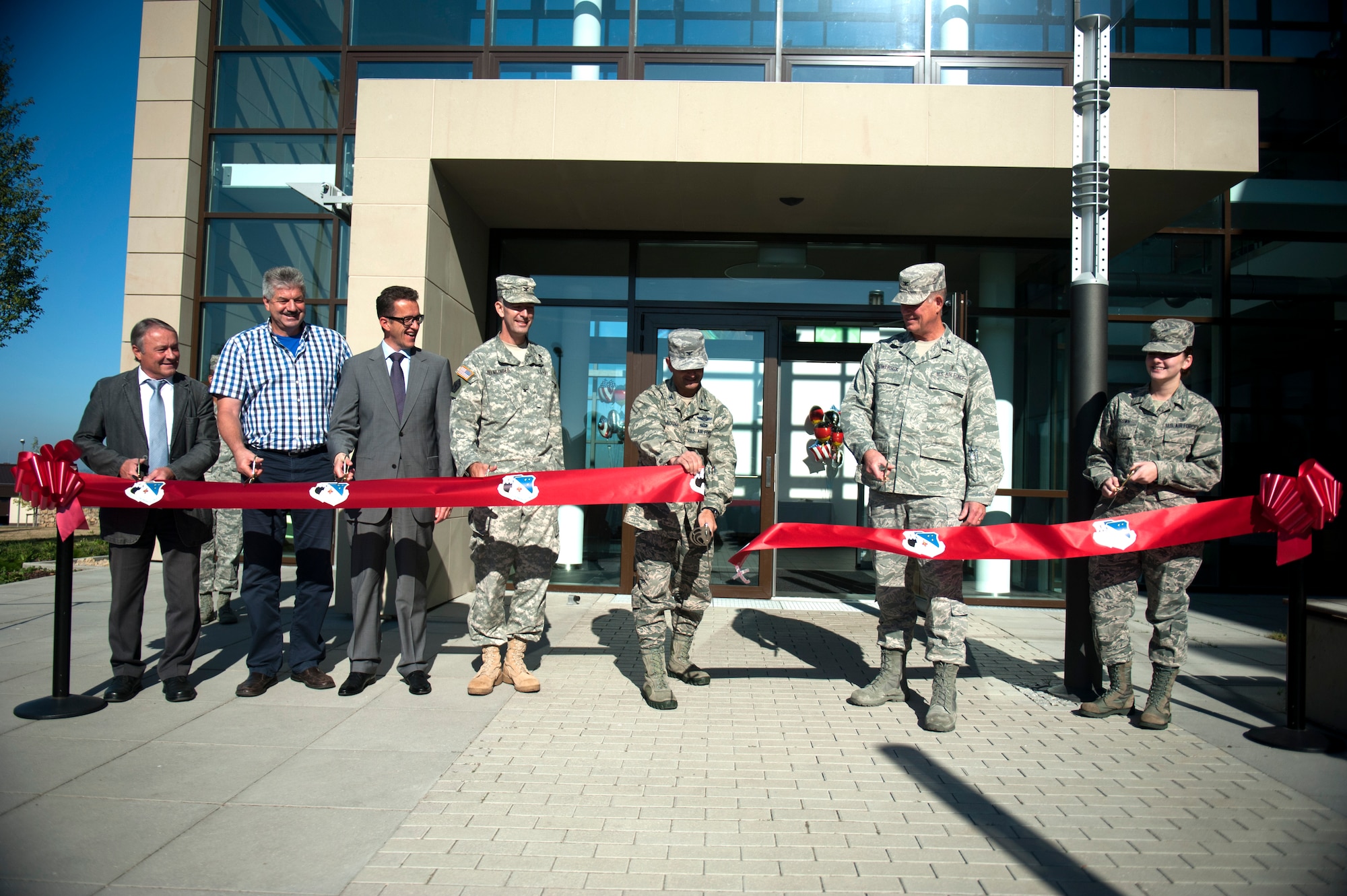 SPANGDAHLEM AIR BASE, Germany – Col. David Julazadeh, 52nd Fighter Wing commander, cuts the ribbon at a ribbon cutting ceremony, along with leadership from the base, U.S. Army Corp of Engineers, and the local community here Sept. 7. The $30.1 million clinic officially opens Sept. 10 and includes a larger parking lot, a 75,000 square foot building, 23 exam rooms, 218 medical professionals, and new medical equipment and furniture.  (U.S. Air Force photo by Airmen 1st Class Gustavo Castillo/Released)