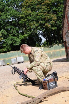 STANTA, Norfolk – Flight Lt. Scott Ripley-Jones, Force Protection Centre and Operational Training Advisory and Standardization Squadron, RAF Honington, makes tracking signs in the sand with a training weapon for other military members to interpret and gain information during a mission rehearsal exercise Sept. 4, 2012, at Stanford Training Area, Thetford.  British Royal Air Force members from 15 Sqdn, RAF Honington; No. 2 Tactical Police Squadron, RAF Henlow; and No. 7 Force Protection Wing Headquarters, RAF Coningsby, worked alongside 100th Security Forces Squadron personnel during the exercise to provide the final stages of training before the British troops deploy to Afghanistan. (U.S. Air Force photo/Karen Abeyasekere)