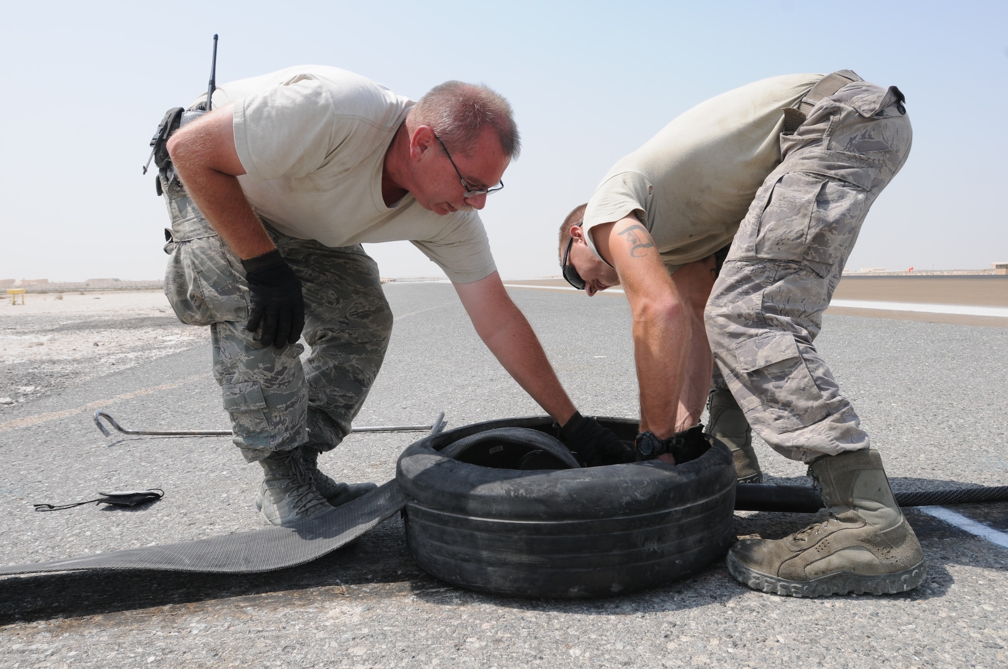 SOUTHWEST ASIA -- U.S. Air Force Master Sgt. Robert Marshall, 380th Expeditionary Civil Engineer Squadron Barrier Maintenance NCO in charge, and Senior Airman Dustin Davidson, 380th ECES Barrier Maintenance technician, attach the mobile aircraft arresting system's nylon tape to the system's wire cable here Sept. 5, 2012. The MAAS is a cable and braking system placed across an end of the runway to catch fighter aircraft that are experiencing a situation where they cannot stop. (U.S. Air Force photo/Tech. Sgt. Amanda Savannah)