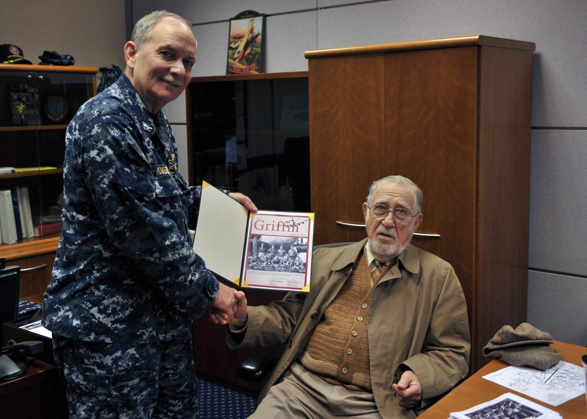 RAF MILESWORTH, United Kingdom - Navy Capt. Gary Powers, Joint Intelligence Operations Center - Europe Analytic Center deputy commander, presents a certficate to retired Air Force Lt. Col. Albert Levin honoring his return to his Word War II base at RAF Molesworth. Levin was a navigator on a B-17G "Flying Fortress." (U.S. Air Force photo by Staff Sgt. Javier Cruz)