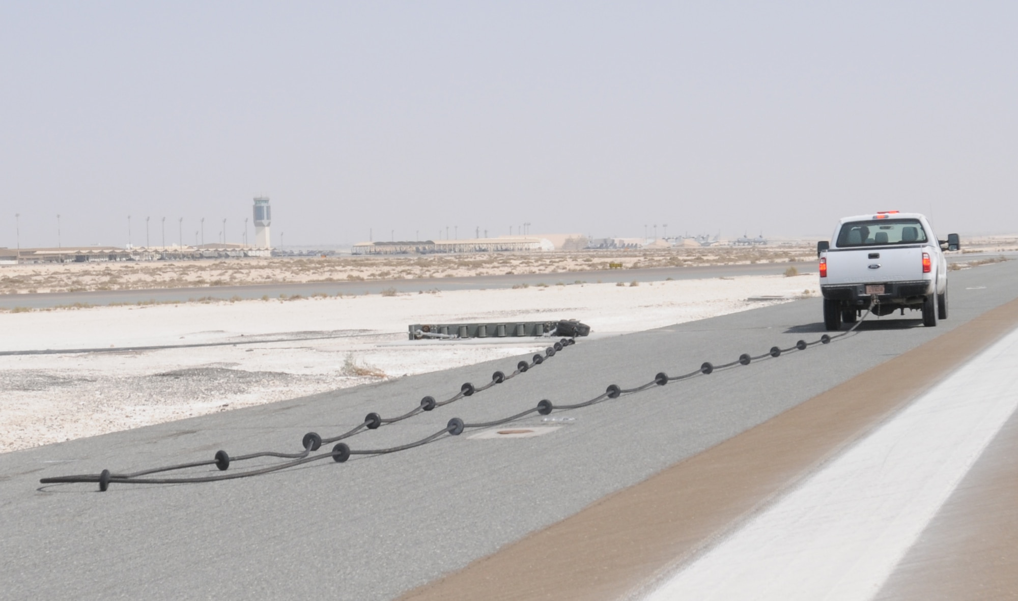 SOUTHWEST ASIA -- The 380th Expeditionary Civil Engineer Squadron Barrier Maintenance team tows the mobile aircraft arresting system cable into place here Sept. 5, 2012. The MAAS is a cable and braking system placed across an end of the runway to catch fighter aircraft that are experiencing a situation where they cannot stop. (U.S. Air Force photo/Tech. Sgt. Amanda Savannah)