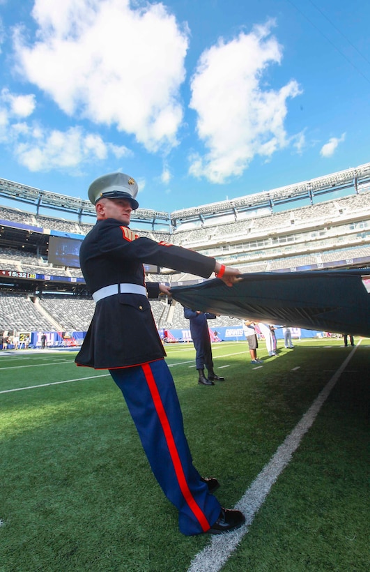 EAST RUTHERFORD, N.J. – Staff Sgt. Richard Ison, a recruiter with Recruiting Station New Jersey, along with other Marines, sailors, Coast Guardsmen , airmen and soldiers unfurled an American flag across the field during a ceremony practice before the New York Giants versus Dallas Cowboys game at MetLife Stadium, Sept. 5 .  More than 60 service members presented the large flag as Queen Latifah sang the national anthem.  (U.S. Marine Corps photo by Cpl. Caleb T. Gomez).