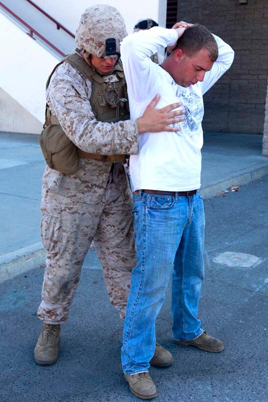 A role player simulating an employee for the United States Agency for International Development, is searched by Sgt. George E. Zeek, a squad leader with the Military Police Detachment, Combat Logistics Battalion 15, 15th Marine Expeditionary Unit, during a non-combatant evacuation operation exercise, at Marine Corps Air Station Camp Pendleton, Calif., Aug. 20. The 15th MEU was conducting the training as part of Certification Exercise, their final pre-deployment training. CERTEX is different than previous exercises because Marines and Sailors do not know the training scenario in advance. They have to react quickly using the Marine Corpsâ€™ Rapid Response Planning Process, which is the process leaders use to prepare for missions the unit will execute.