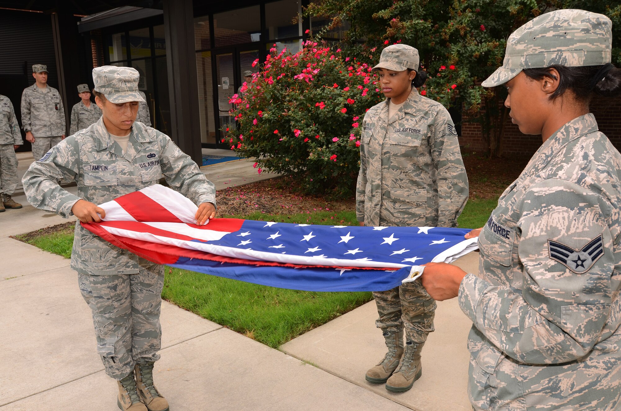 Master Sgt. Lena Tamplin folds the base flag as Senior Airman Cynthia Carson holds it taught and Staff Sgt. Ashley Hanshaw stands by, Sept.8. The 94th Communications Squadron was selected to perform a retreat ceremony at Dobbins Air Reserve Base during the September weekend.  (U.S. Air Force photo/Brad Fallin)
