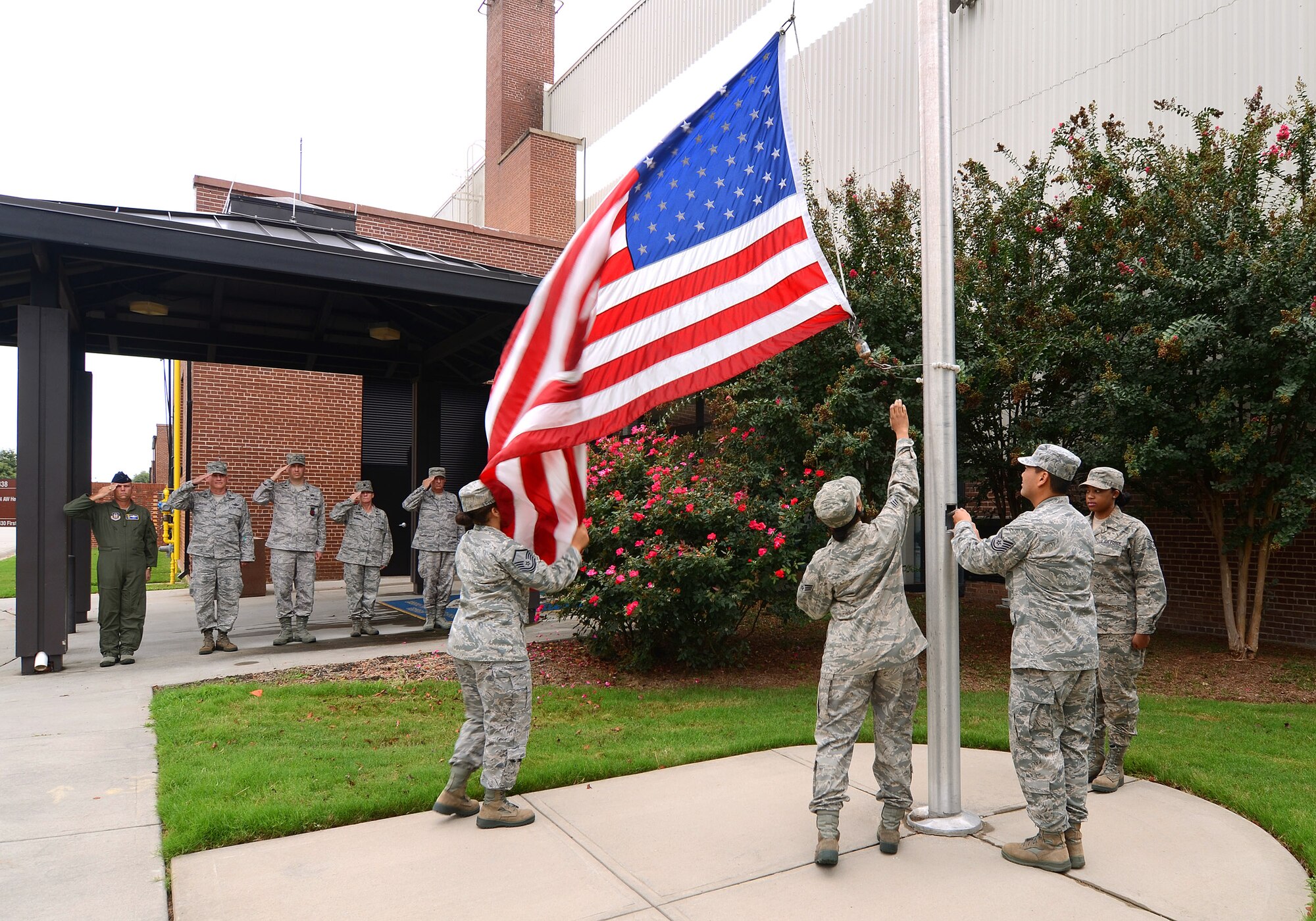 Master Sgt. Lena Tamplin gathers the base flag as Senior Airman Cynthia Carson prepares to unhook the halyard; Tech. Sgt. Stephen Athey lowers the flag while Staff Sgt. Ashley Hanshaw stands by, Sept.8. Members of the 94th Communications Squadron were responsible for performing a retreat ceremony at Dobbins Air Reserve Base during the September drill weekend.  (U.S. Air Force photo/Brad Fallin)