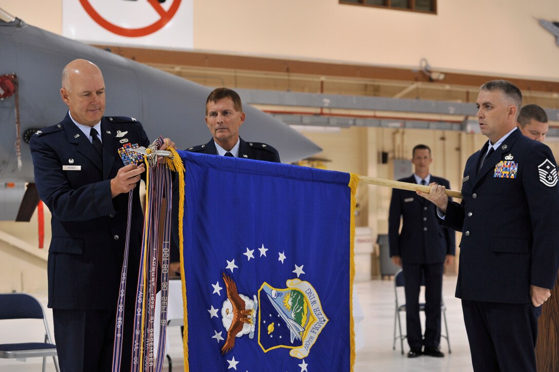 120th Fighter Wing commander Col. J. Peter Hronek attaches the Air Force Outstanding Award streamer to the Wing's flag during the AFOUA presentation ceremony Sept. 9, 2012.  Montana Air National Guard commander Brig. Gen. Bradley Livingston and 120th Security Forces Squadron first sergeant Master Sgt. Edward McNamee look on.  National Guard photo by Staff Sgt. John Turner.
