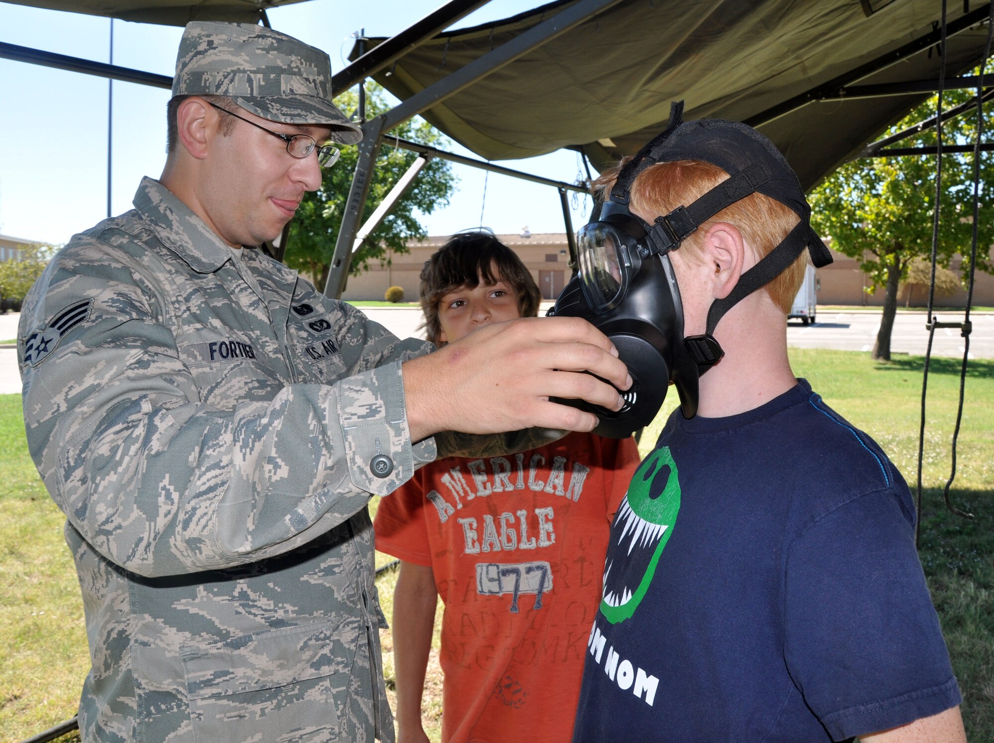 Senior Airman William Fortier, 931st Civil Engineer Squadron, helps a child from Big Brothers Big Sisters of Sedgwick County try on an M-50 Joint Service General Purpose Gas Mask during a demonstration at McConnell Air Force Base, Kan., Sept. 9, 2012.  Children from the Big Brothers Big Sisters organization received a tour of the base, hosted by the 931st Air Refueling Group.  The children were able to observe demonstrations of the many career fields available within the Air Force Reserve.  (U.S. Air Force photo by Staff Sgt. Carrie M. Peasinger)