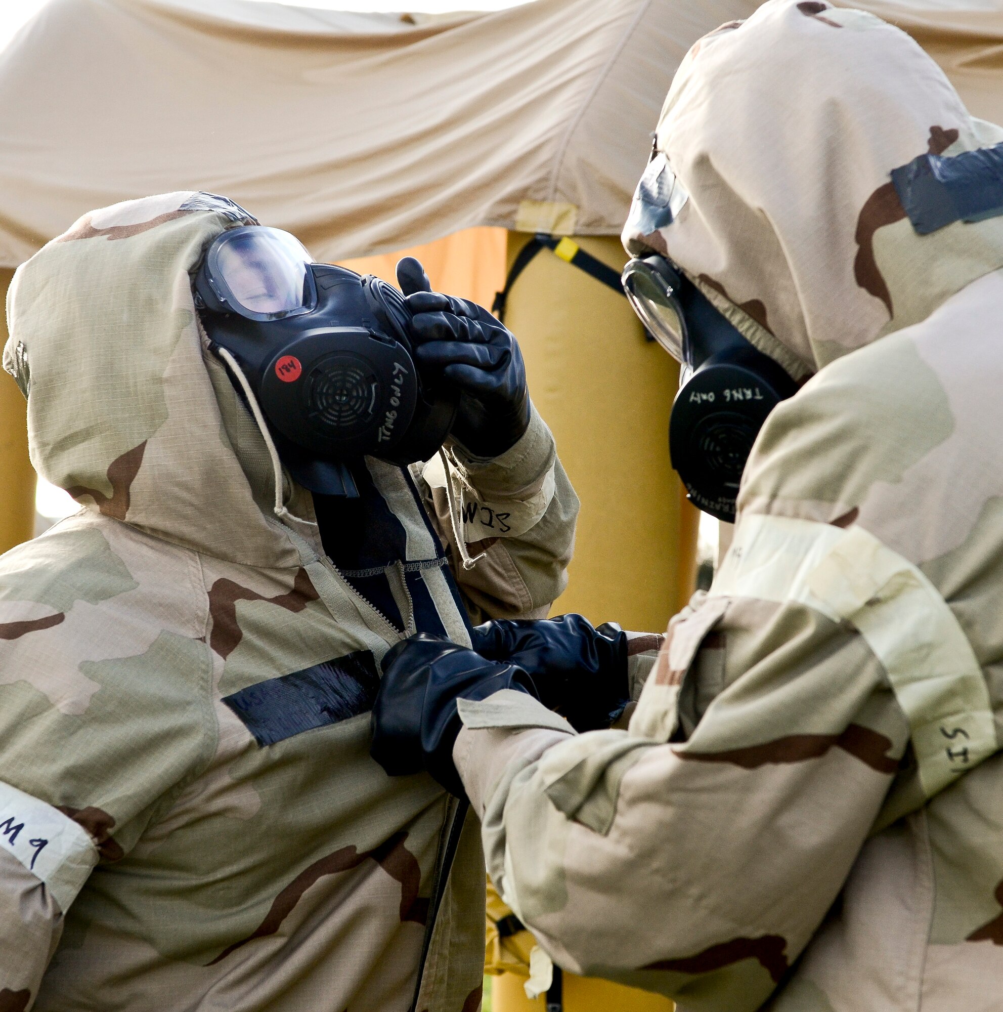 U.S. Air Force Airmen assist one another while processing through a contamination control area during an operational readiness inspection at Robins Air Force Base, Ga., Sept. 6, 2012. More than 500 Airmen simulated a deployment that tested basic knowledge such as self-aid and buddy care, and chemical, biological, radioactive nuclear and explosive responses. (National Guard photo by Master Sgt. Roger Parsons/Released)