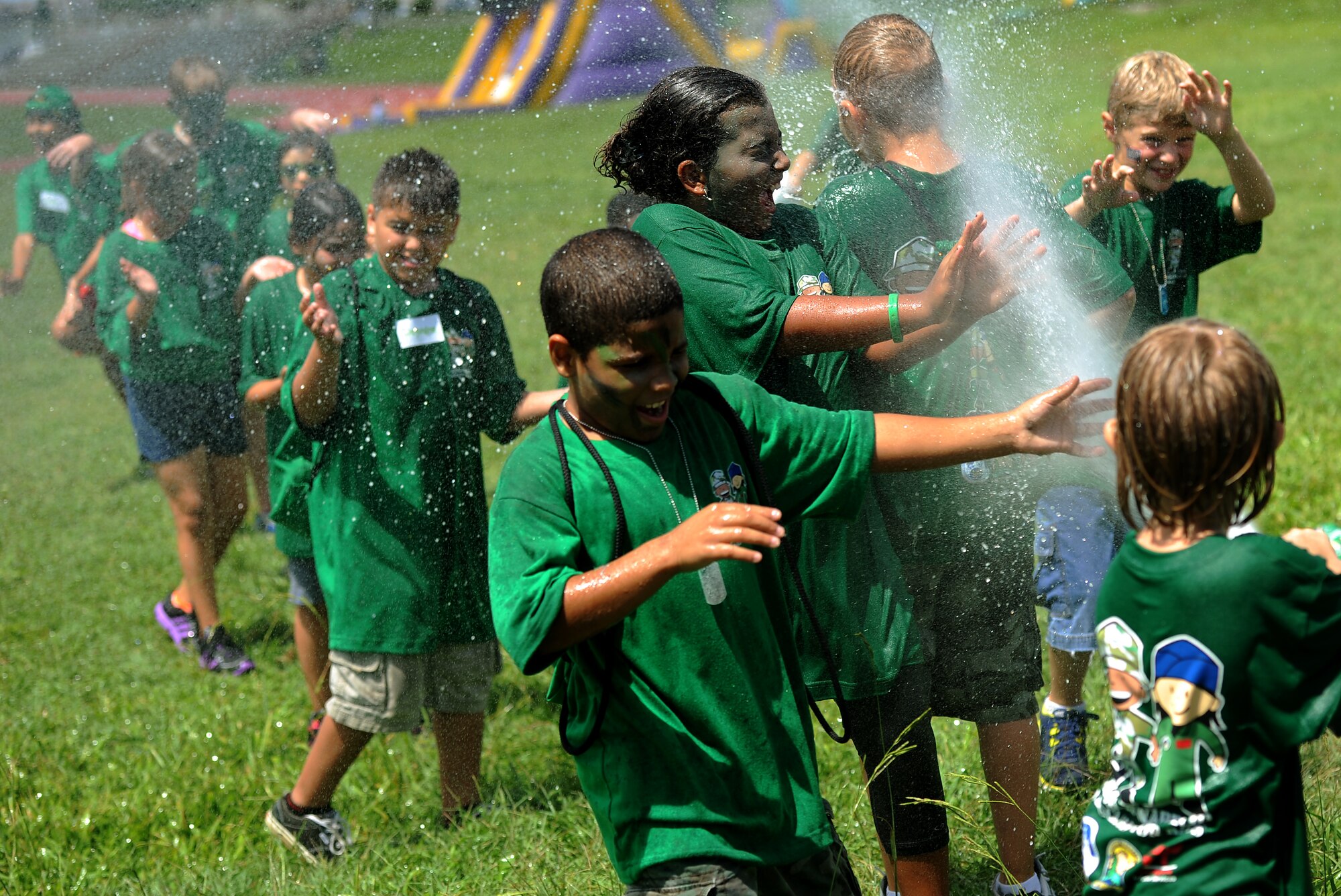 Children from the Green Team douse each other with a fire hose during the Skoshi Warrior held on Kadena Air Base, Sept 8, 2012. The annual event was held to help military children better understand what their parents go though while deploying by giving them a hands on experience and face time with various base support agencies. (U.S. Air Force photo/Staff Sgt. Laszlo Babocsi)