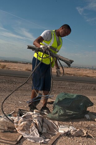 U.S. Air Force Staff Sgt. Jeremy McIntosh, 99th Medical Support Squadron health services management craftsman, picks up trash along side of East El Campo Grande Avenue  Sept. 9 2012, in Las Vegas. Nellis Airmen worked with the City of North Las Vegas during the effort. Fifty-eight Airmen from Nellis Air Force Base volunteered to assist the city of North Las Vegas with a cleanup effort that resulted in 40 tons of debris being removed from local streets in the area. (U.S. Air Force photo by Staff Sgt. Christopher Hubenthal)