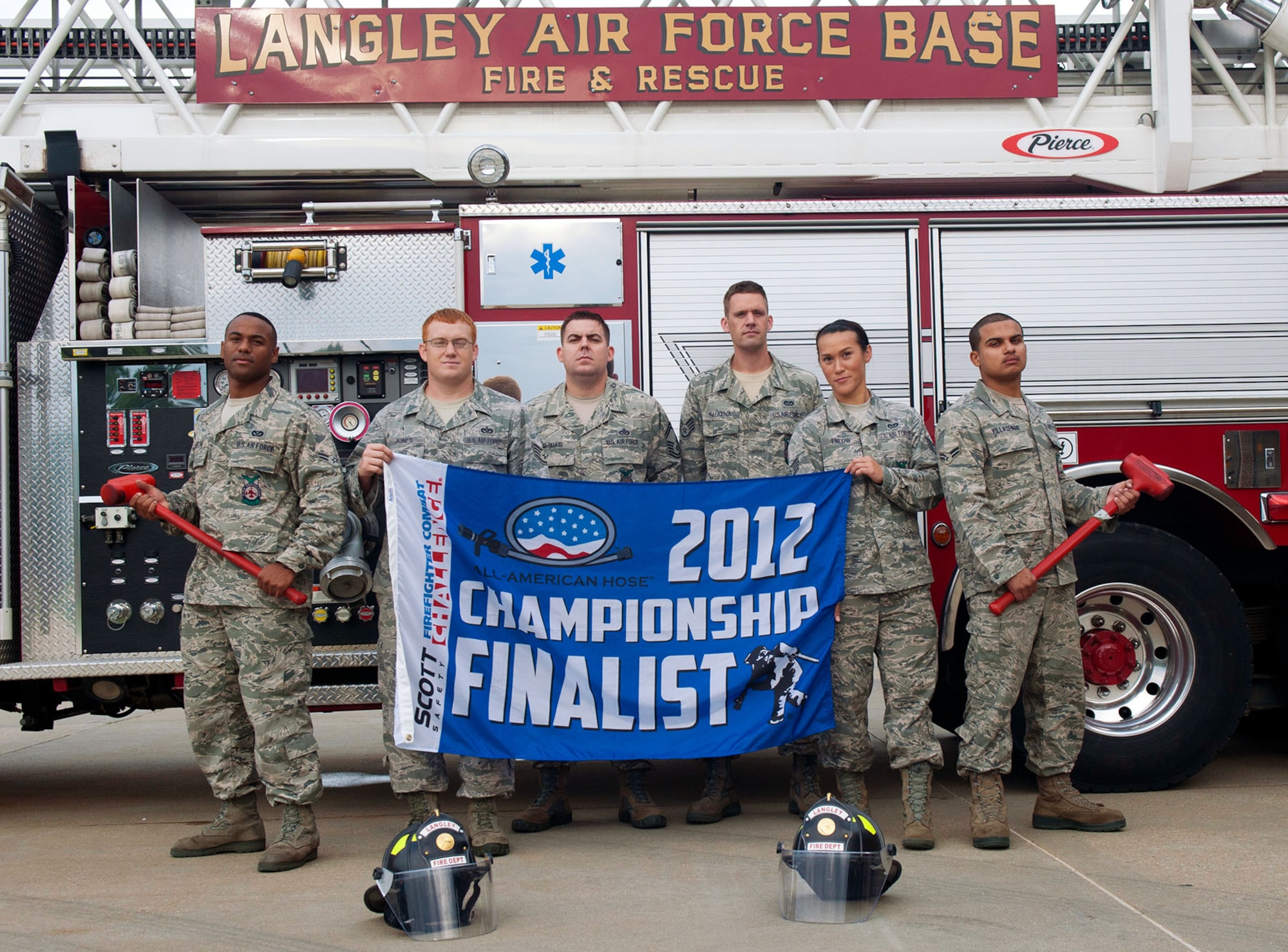 The team of 633rd Civil Engineer Squadron fire protection specialists stand in front of a fire truck holding their championship finalist flag, Aug. 24, 2012, at Langley Air Force Base, Va. The flag was awarded to the team after they qualified for the national Firefighter Combat Challenge, during the regional challenge at Charleston, W.Va. (U.S. Air Force photo by Staff Sgt. John Strong III/Released)