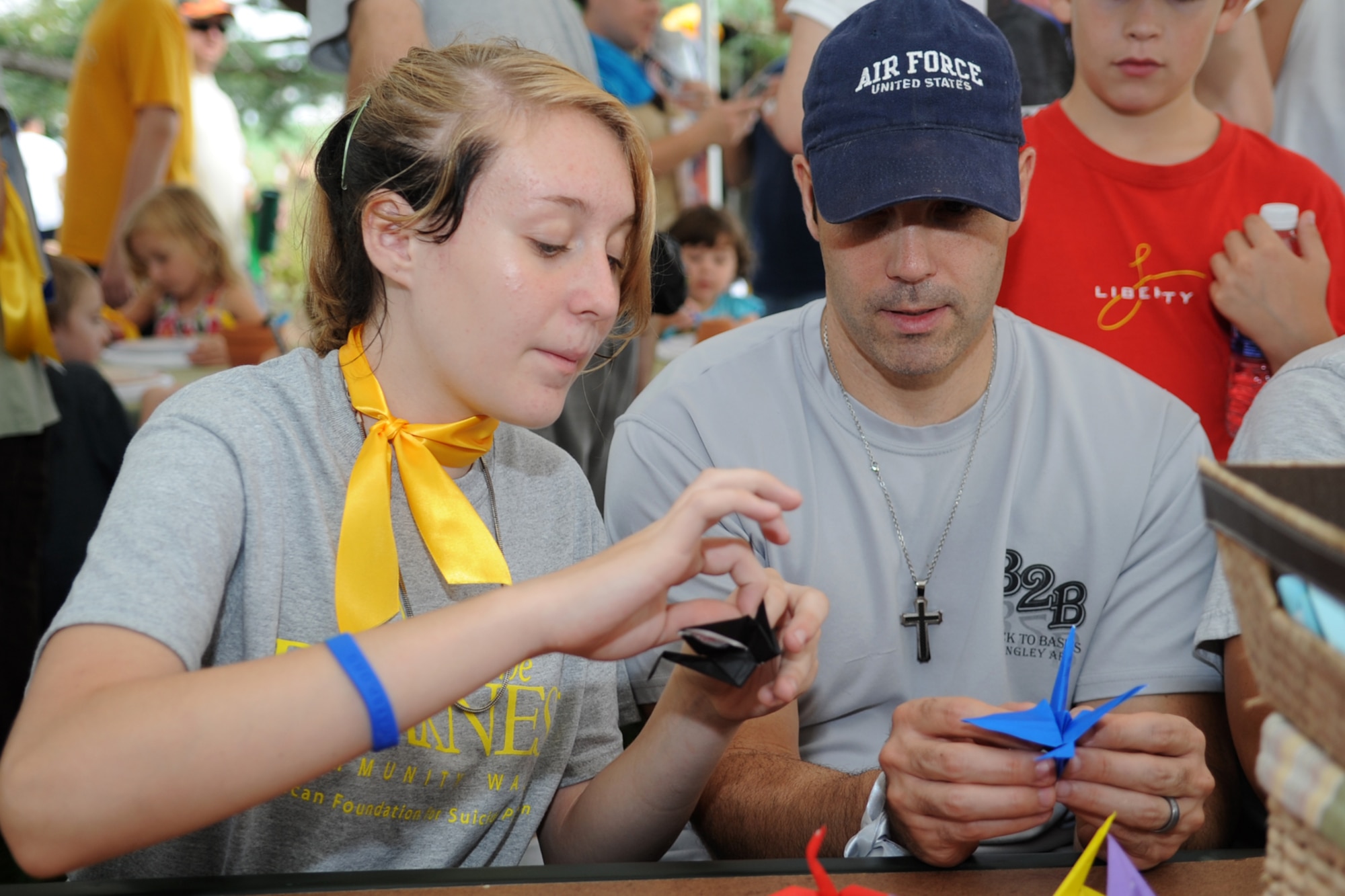 Alexis Green, Out of Darkness volunteer, and U.S. Air Force Master Sgt. Gregory Lambert, 633rd Medical Support Squadron Nutrition Medical Flight noncommissioned officer in charge, make the final folds to an origami paper crane during the Out of the Darkness Walk, designed to promote suicide awareness, at Mount Trashmore Park in Virginia Beach, Va., Sept. 8, 2012. The practice of folding 1,000 cranes represents a form of healing and hope during challenging times. (U.S. Air Force photo by Senior Airman Racheal Watson/Released)