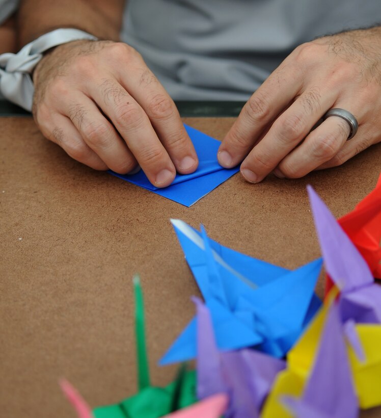 U.S. Air Force Master Sgt. Gregory Lambert, 633rd Medical Support Squadron nutrition medical flight noncommissioned officer in charge, learns to fold an origami paper crane during the Out of the Darkness Walk, which promoted suicide awareness, at Mount Trashmore Park in Virginia Beach, Va., Sept. 8, 2012. The Survivors of Suicide Group, who helped sponsor the event, adopted the crane to express the spirit of participation and hope for peace. (U.S. Air Force photo by Senior Airman Racheal Watson/Released)