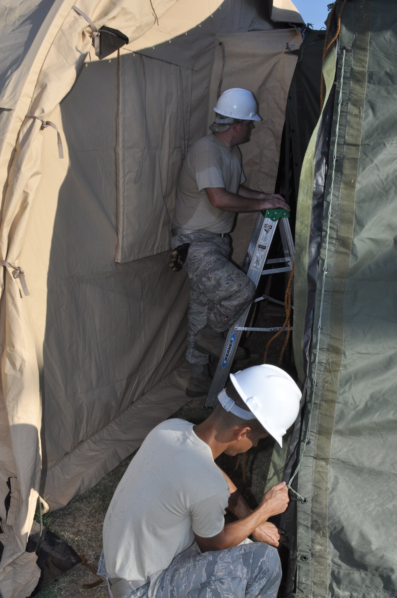 FSV team members work on securing the connection tunnel between the Single Pallet Expeditionary Kitchen and the dining tent as part of the Hennessy Trophy evaluation during the August UTA.  Temperatures were reported in the low 100 degree range for the weekend.  (U.S. Air Force photo/Tech. Sgt. Chris Bolen)
