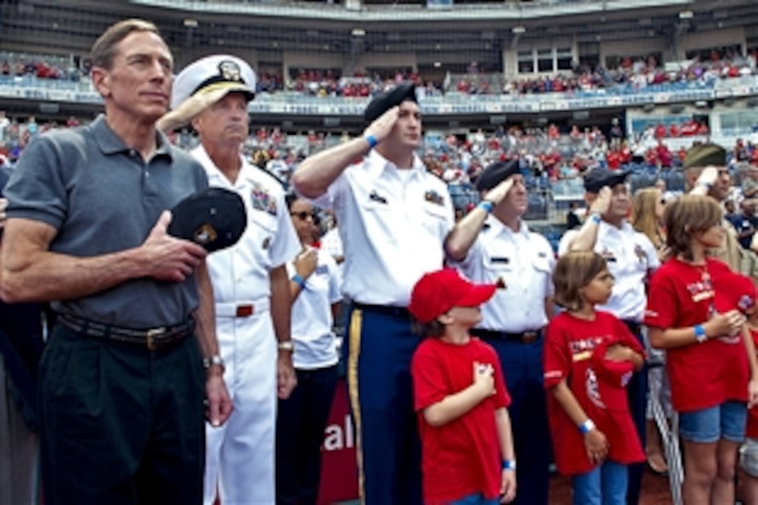 Navy Adm. James A. Winnefeld Jr., second from left, vice chairman of the Joint Chiefs of Staff, and retired Army Gen. David H. Petraeus, far left, CIA director, render honors during the playing of the national anthem before the Washington Nationals-Miami Marlins game in Washington, D.C., Sept. 9, 2012. Winnefeld also met with players from the Wounded Warrior Amputee Softball Team, other veterans and families.