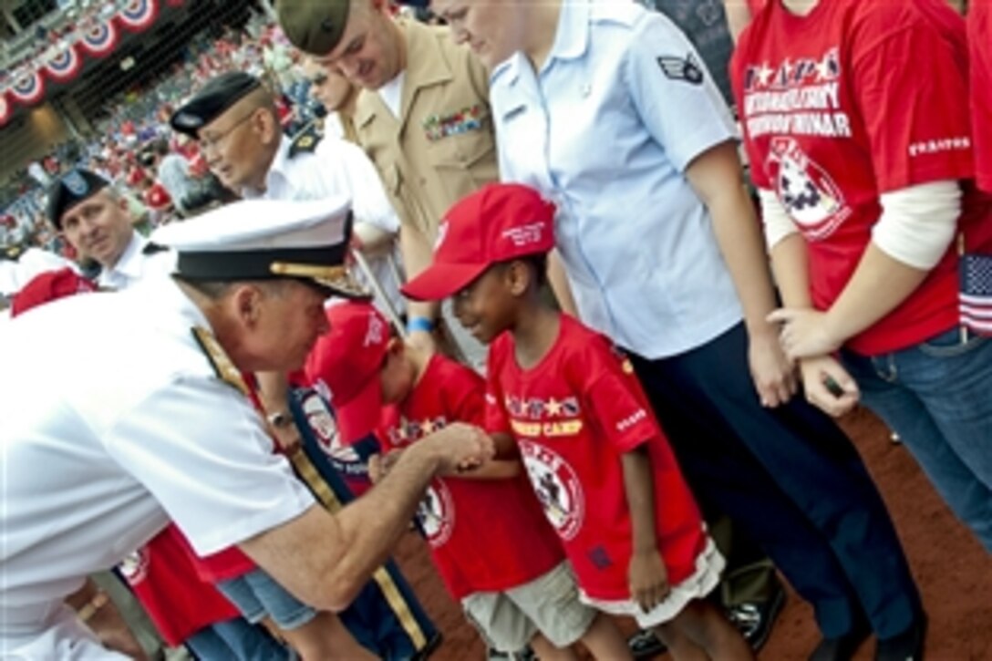 Navy Adm. James A. Winnefeld Jr., vice chairman of the Joint Chiefs of Staff, gives a coin to a child from the Tragedy Assistance Program for Survivors before the Washington Nationals- Miami Marlins game in Washington, D.C., Sept. 9, 2012. 