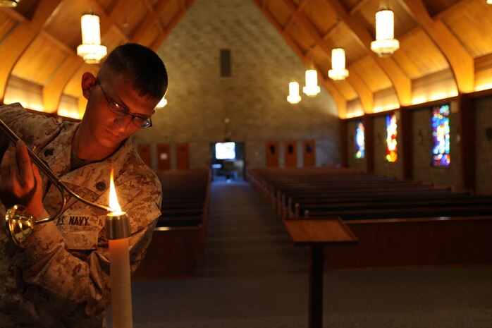 Navy Petty Officer 2nd Class Bradley Brouwer, a religious program specialist with the on base chapel, lights the candles necessary for Wednesday night mass, August 7.
