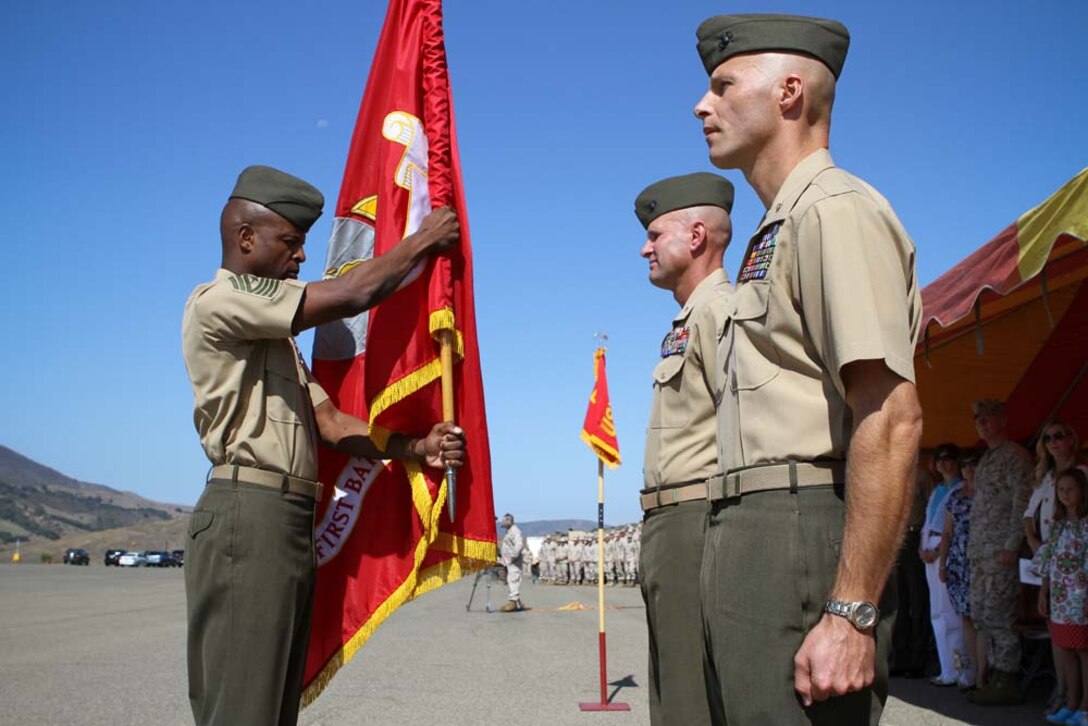 Sergeant Major Angelo R. Scott, the sergeant major of 1st Battalion, 4th Marine Regiment, hands the battalion colors to Lt. Col. Kevin A. Norton, who relinquished command of the battalion to Maj. Christopher J. Bronzi, during a change of command ceremony here Sept. 6, 2012. After receiving the battalion colors from the sergeant major, Norton, a Wilkes-Barre, Pa., native, then handed the colors to Bronzi, a native of Poughquag, N.Y., signifying the command of the battalion was passed to him.