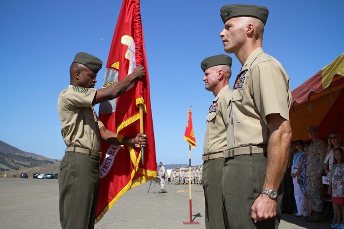 Sergeant Major Angelo R. Scott, the sergeant major of 1st Battalion, 4th Marine Regiment, hands the battalion colors to Lt. Col. Kevin A. Norton, who relinquished command of the battalion to Maj. Christopher J. Bronzi, during a change of command ceremony here Sept. 6, 2012. After receiving the battalion colors from the sergeant major, Norton, a Wilkes-Barre, Pa., native, then handed the colors to Bronzi, a native of Poughquag, N.Y., signifying the command of the battalion was passed to him.