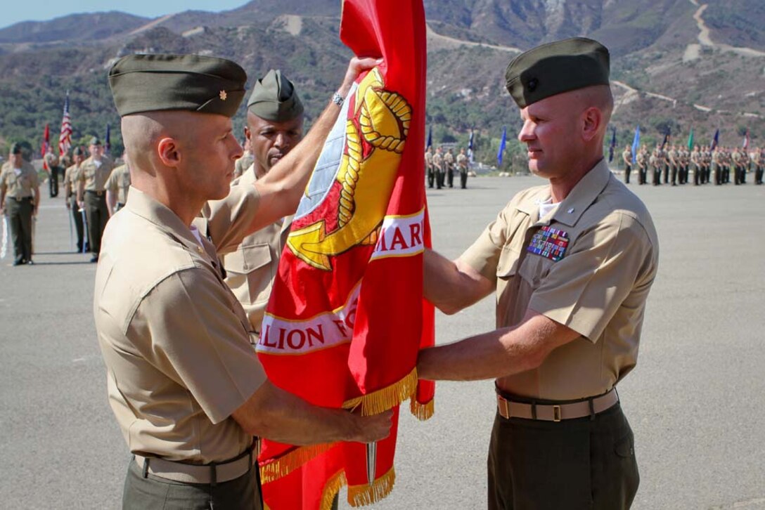 Lieutenant Colonel Kevin A. Norton (right) relinquishes command of 1st Battalion, 4th Marine Regiment, to Maj. Christopher J. Bronzi as he hands him the battalion colors during a change of command ceremony here Sept. 6, 2012.