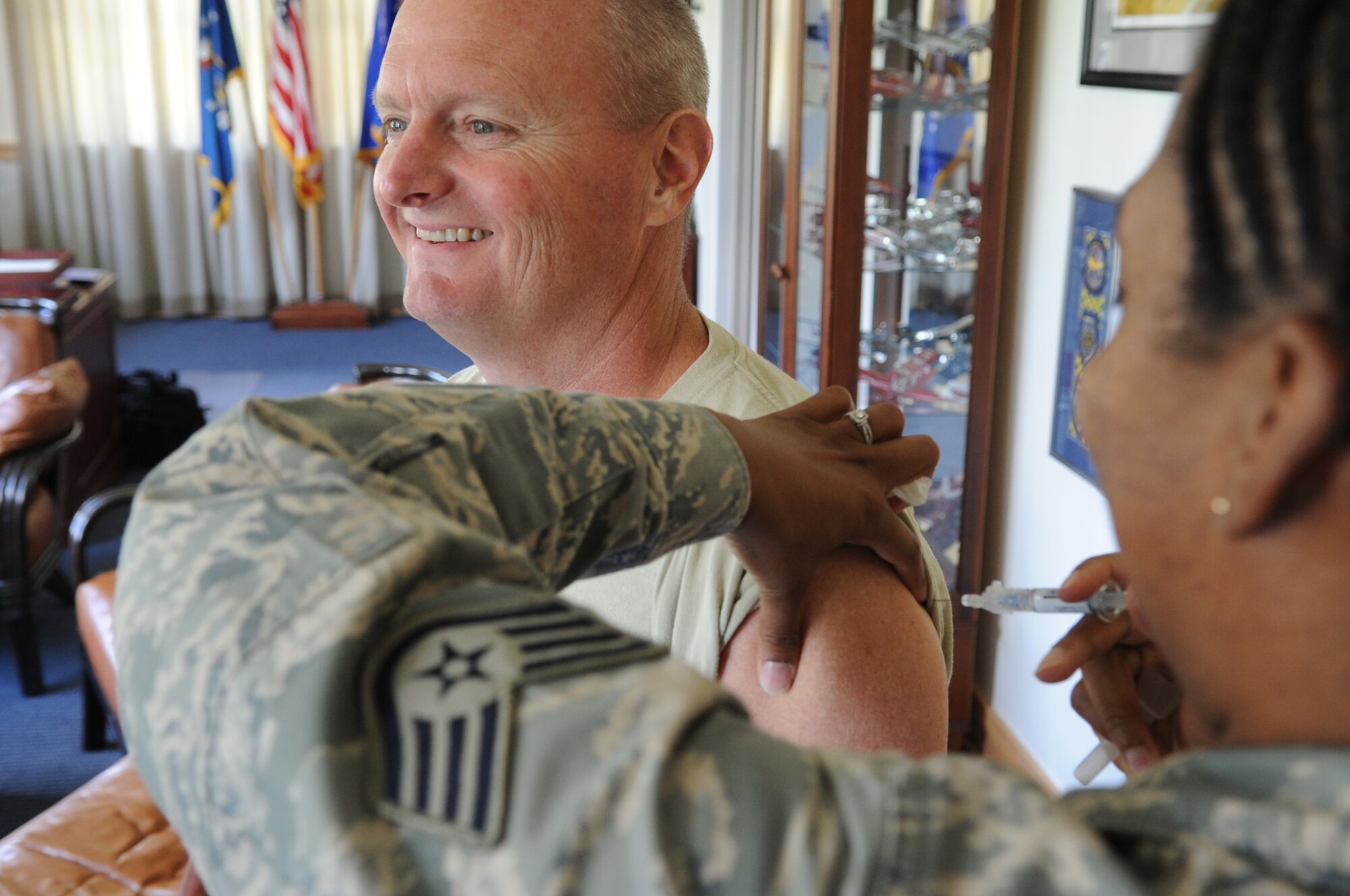Staff Sgt. Aimee Braxton, 15th Medical Operations Squadron NCO in Charge of Immunizations, gives a shot to Col. Terry Scott, 15th Wing vice commander, Sept. 6 at Joint Base Pearl Harbor-Hickam, Hawaii. These early immunizations were precursors to a larger mass-immunization exercise, or SHOTEX, to be conducted Sept. 18-20. (U.S. Air Force photo by Staff Sgt. Mike Meares)
