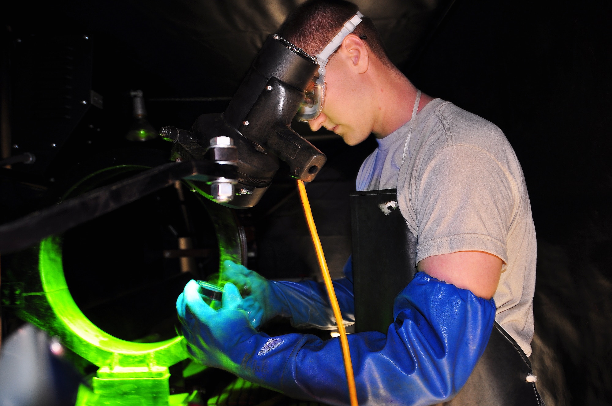 Airman 1st Class Dylan Brown, 94th Airlift Wing non-destructive inspection specialist, uses a magnetic particle machine to detect cracks on a metal test piece. Cracks on the test piece appear bright green under black light, due to liquid dye penetrant. (U.S. Air Force photo/Senior Airman Elizabeth Van Patten)